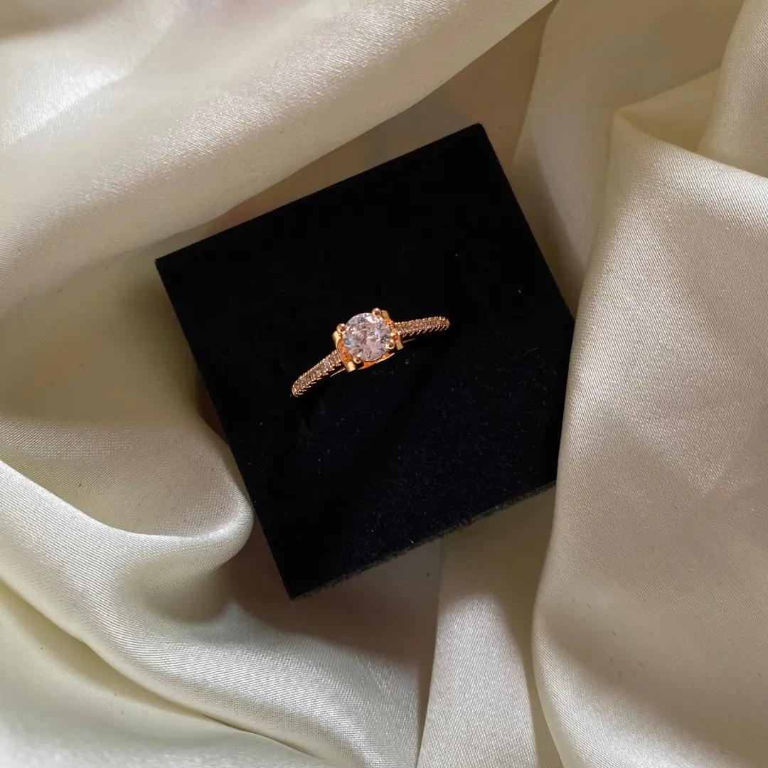 Round cubic zirconia solitaire in a four-prong setting with pavé shoulders on a slim rose gold-plated band