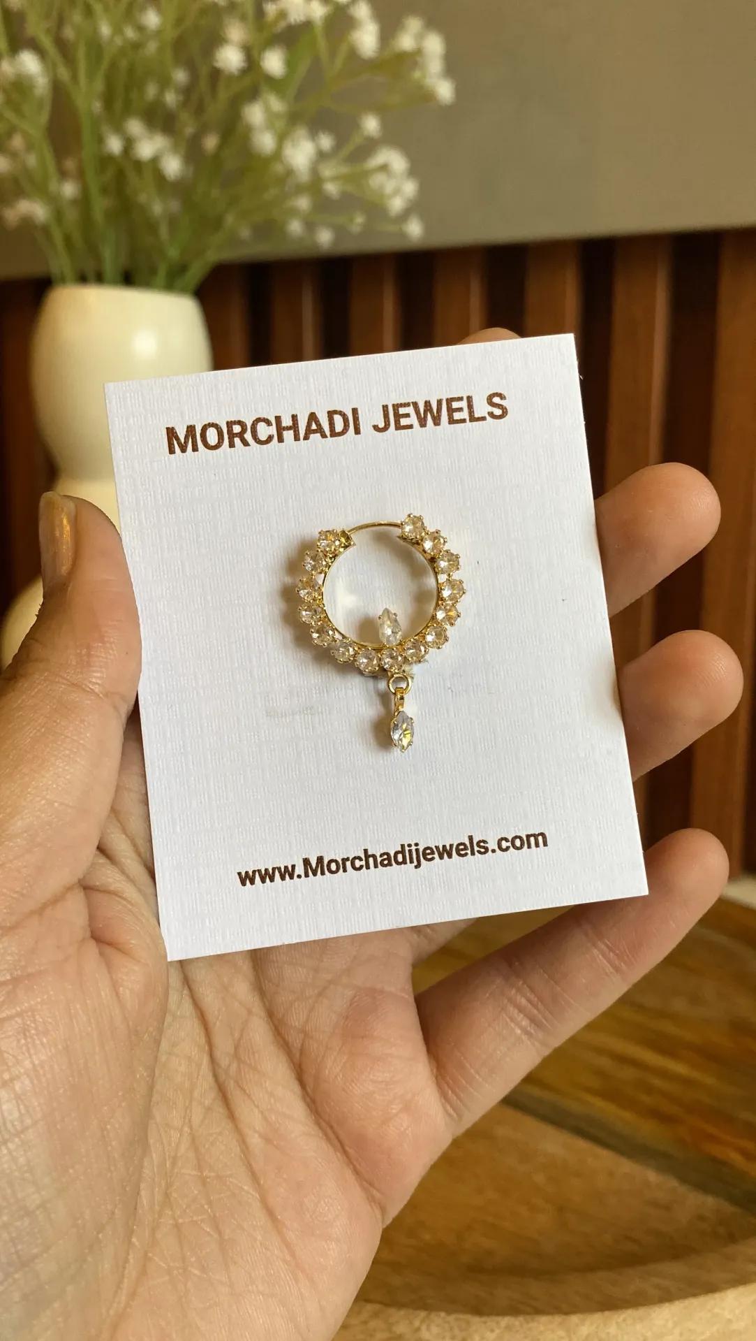 Gold-toned nath with clear cubic zirconia stones set edge to edge around the ring and a teardrop drop