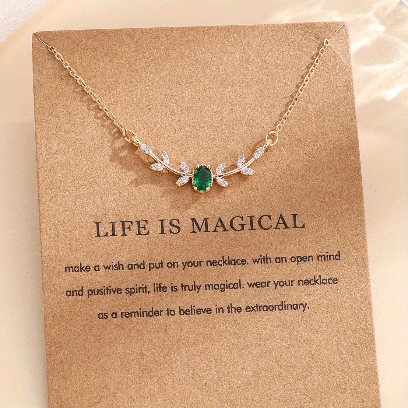Gold-toned necklace with a central emerald-green oval stone and clear marquise leaf stones