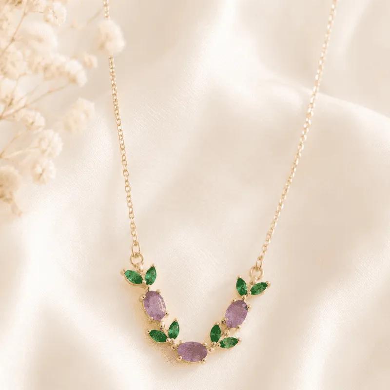 Gold-plated V-shaped vine necklace with pale lavender cubic zirconia stones and emerald-green leaf accents