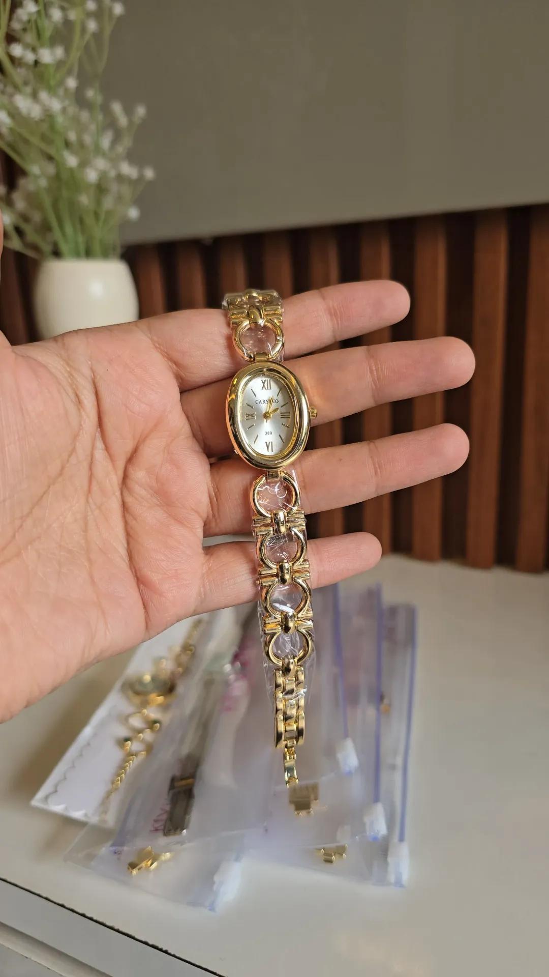 Gold-tone circular-link bracelet watch with a white oval dial and roman numerals