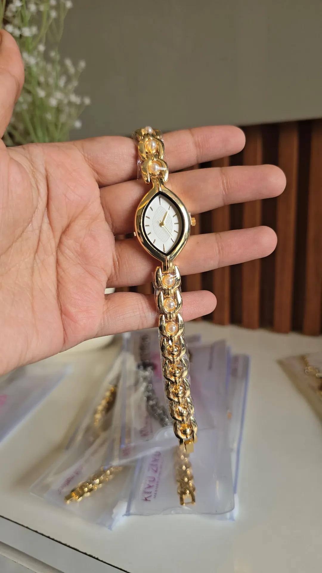 Gold-tone bold-link chain bracelet watch with a leaf-shaped white dial and pearl-look beads