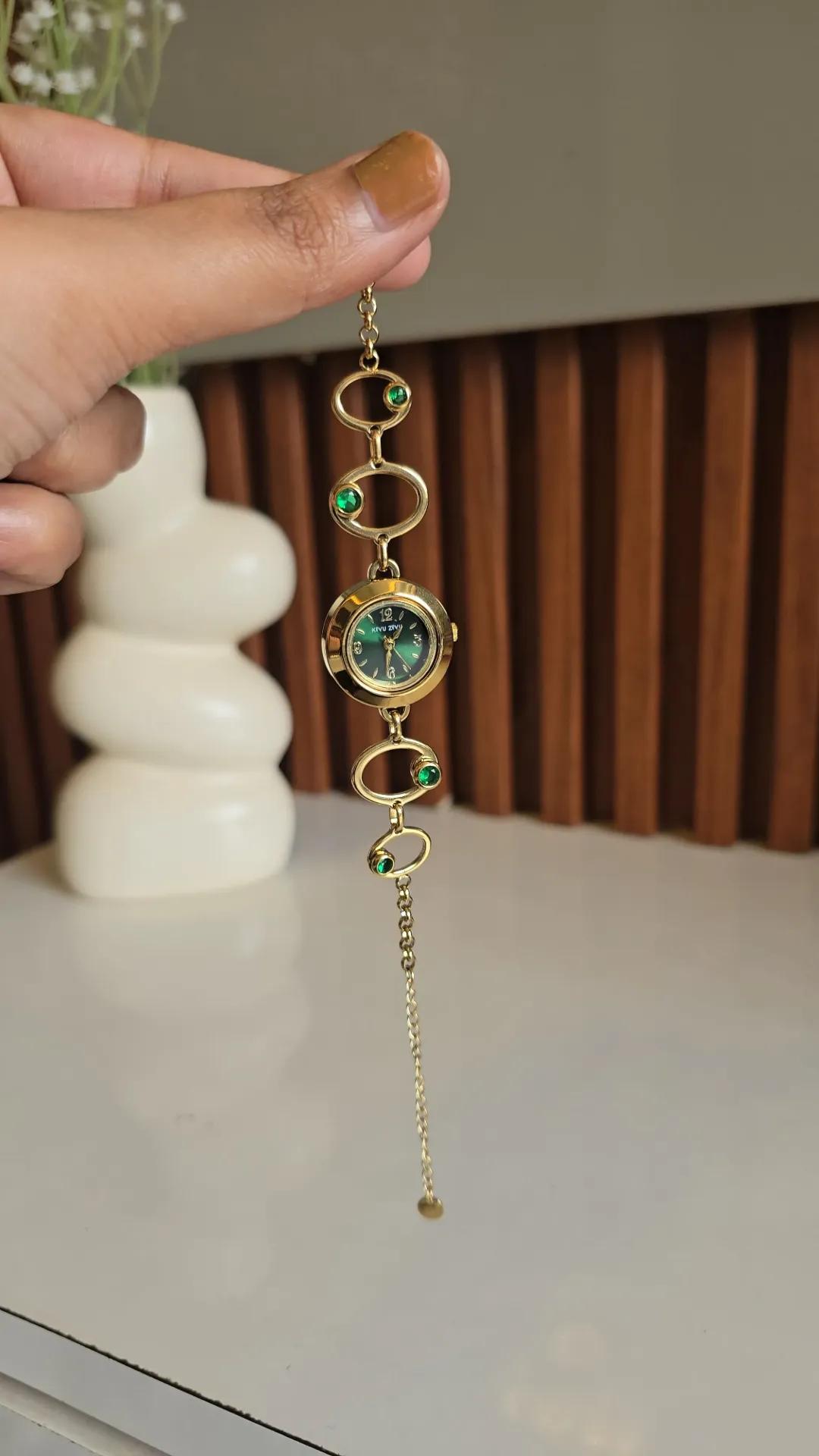 Gold-tone open-oval link bracelet watch with a green stone-set dial